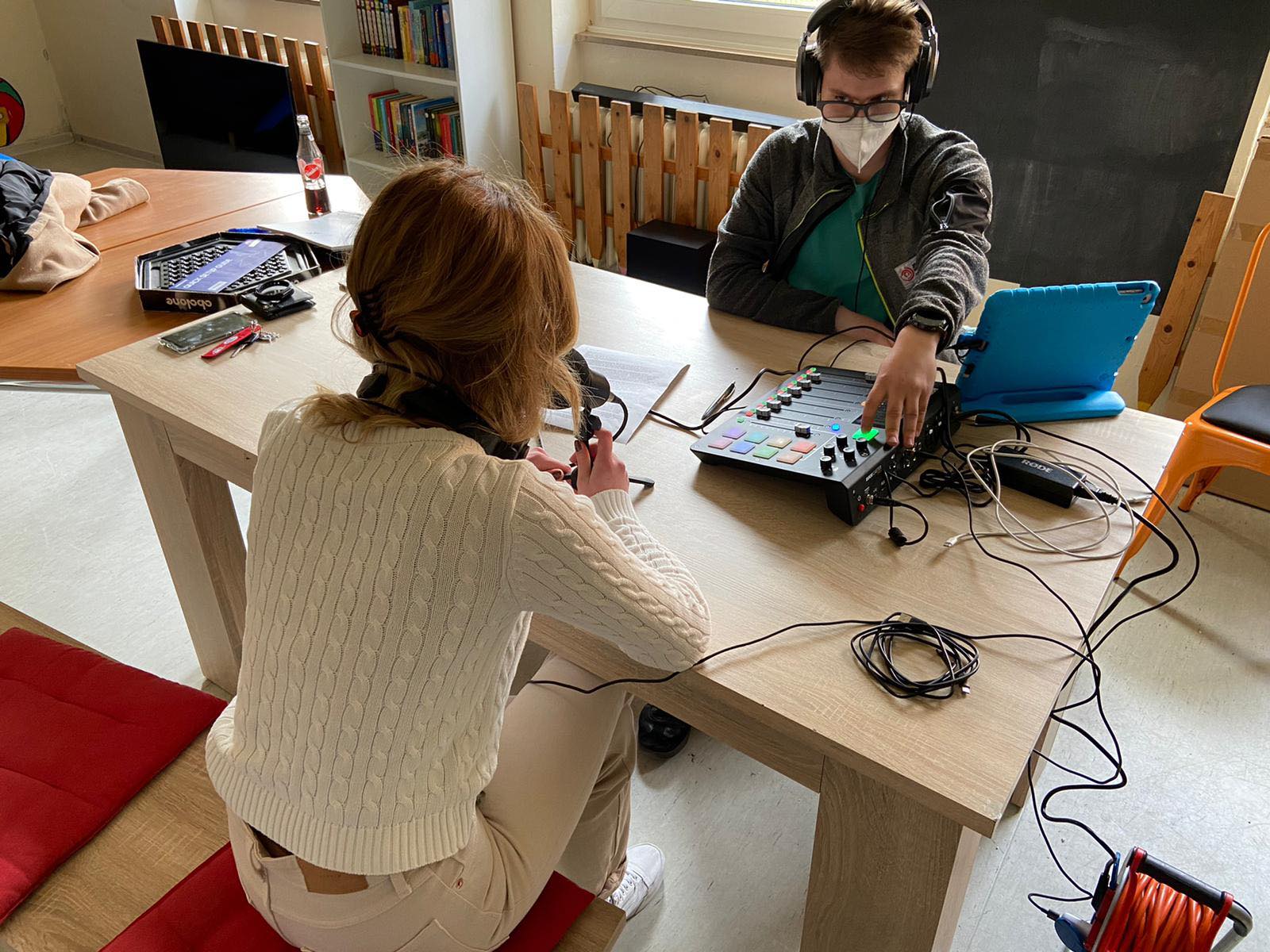 Zwei Jugendliche sitzen sich an einem Tisch gegenüber und nehmen einen Podcast auf.