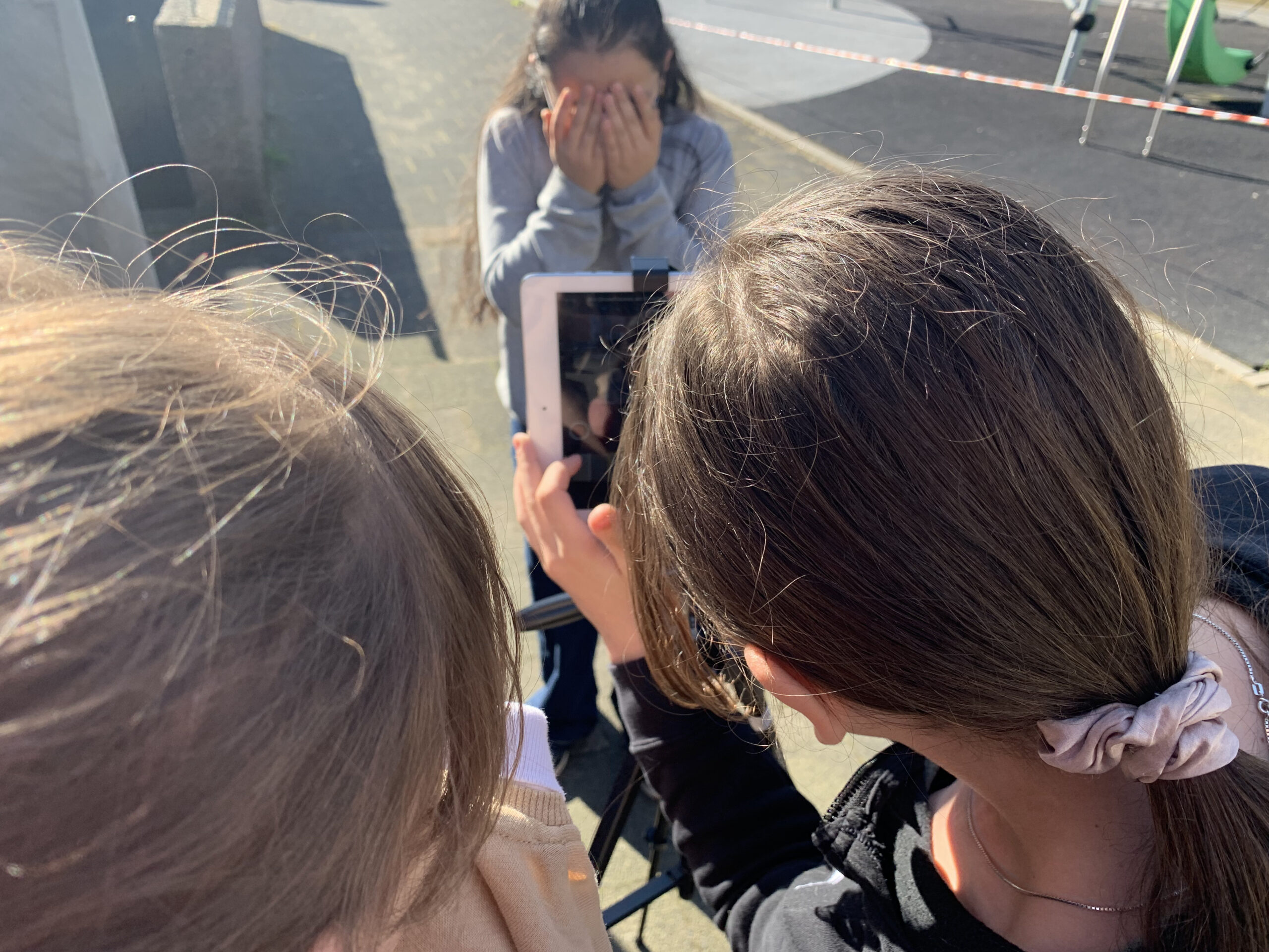 zwei Jugendliche filmen mit einem Tablet eine dritte Person
