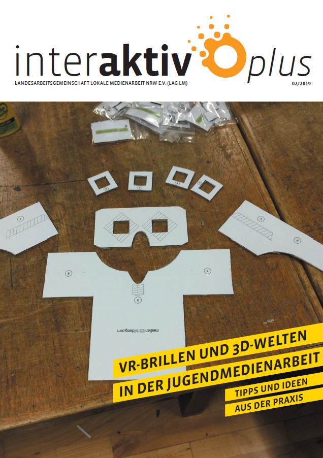 Papierbastelbogen für eine VR-Brille auf einem Holztisch, umgeben von kleinen Papierrahmen und Bastelmaterialien