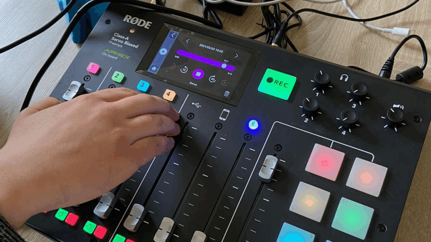 Eine Hand bedient ein Audio Board mit verschiedenen Reglern
