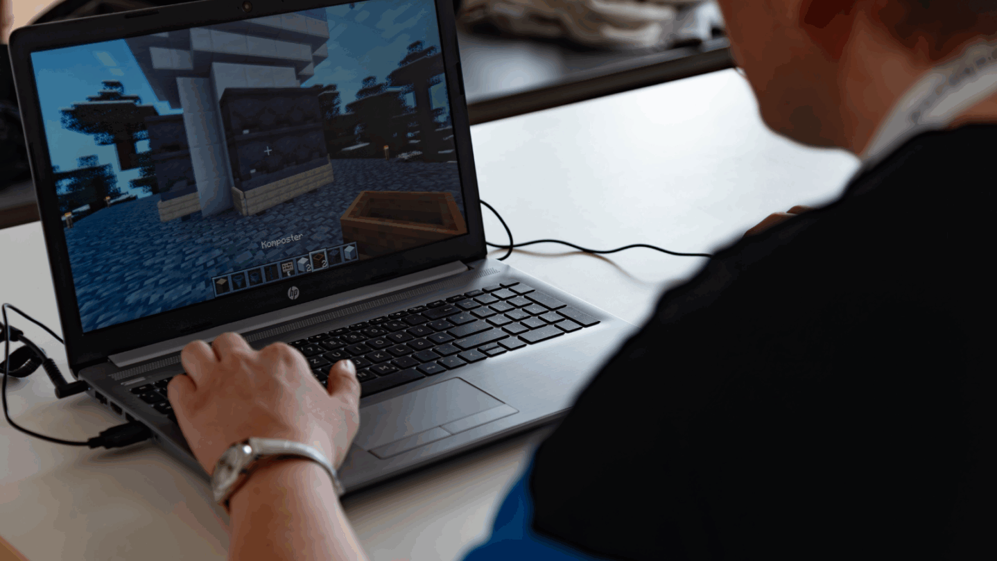 Eine Person spielt an einem Laptop Minecraft
