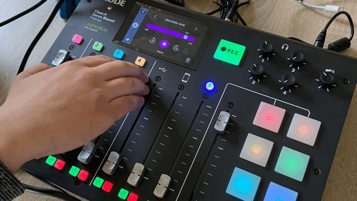 Eine Hand bedient ein Audio-Mischpult.