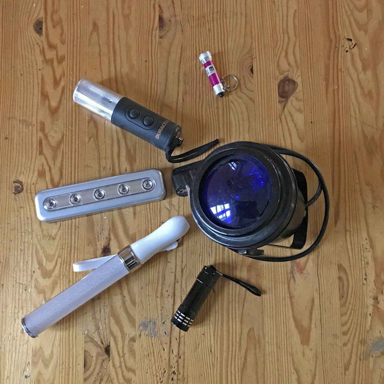 Verschiedene Lichtquellen auf einem Tisch: Taschenlampe, bunte Leuchtstäbe, Disco-Licht