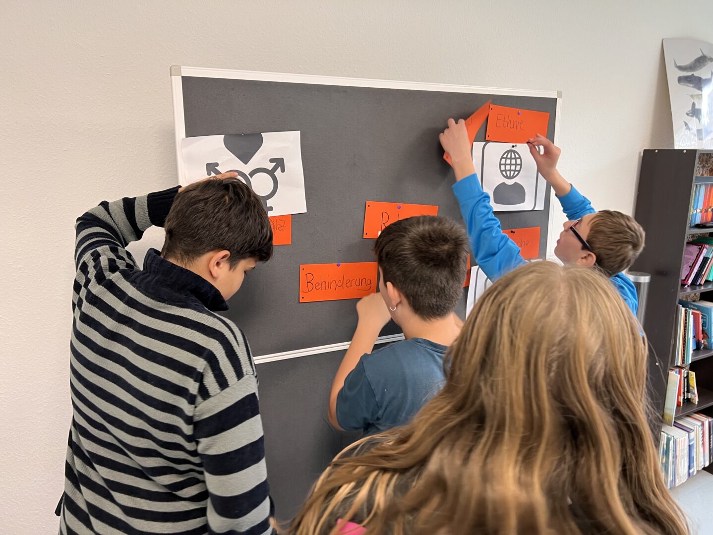 Jugendliche beim Diversitätsquiz: Begriffe und Piktogramme werden einander zugeordnet und an eine Pinnwand gehängt.