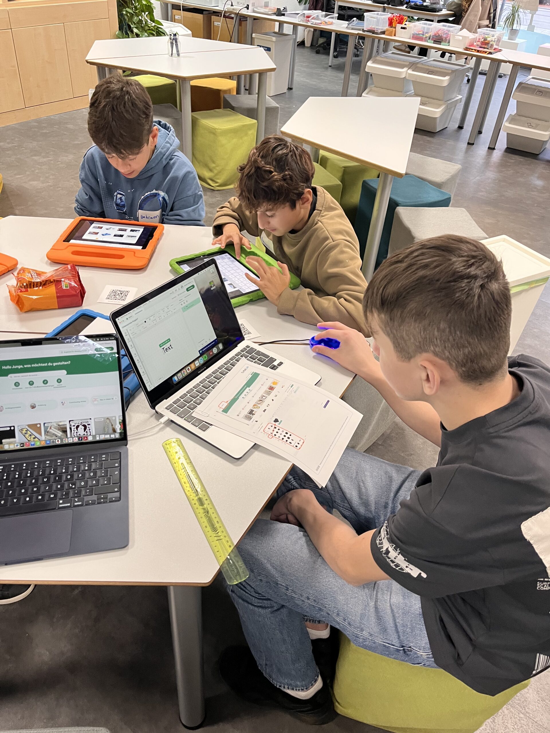 Jugendliche sitzen in einem MakerSpace an einem Tisch und arbeiten an Laptops