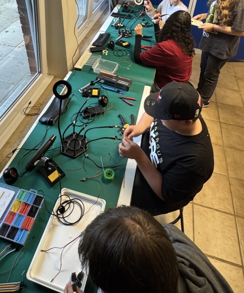 Jugendliche an einer Making Station beim Löten, Schrauben und Basteln
